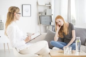 struggling female patient talks to concerned female therapist taking notes about 12 step meetings