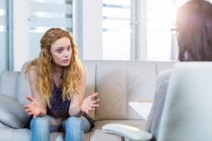 woman holds her hands out and talks to her female therapist during cognitive behavioral therapy