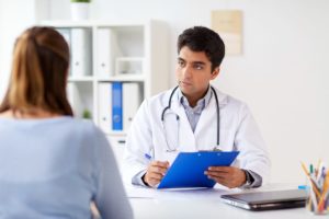 male doctor takes notes on clipboard while female patient talks to him in a heroin addiction treatment center