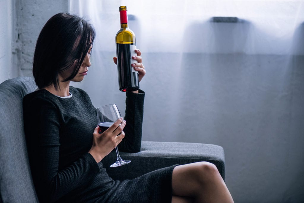 alcohol and depression, woman sitting alone drinking wine