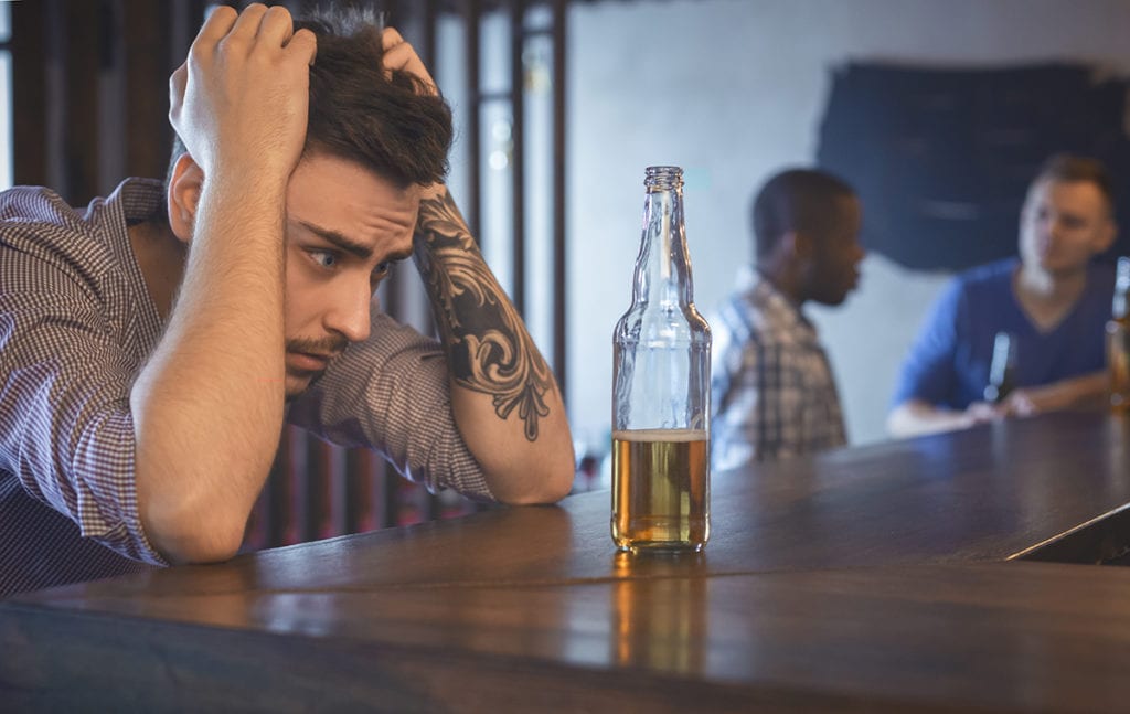 am i an alcoholic, young man staring at beer bottle in bar