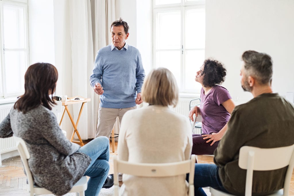 cbt vs dbt, A man talking to other people during group therapy