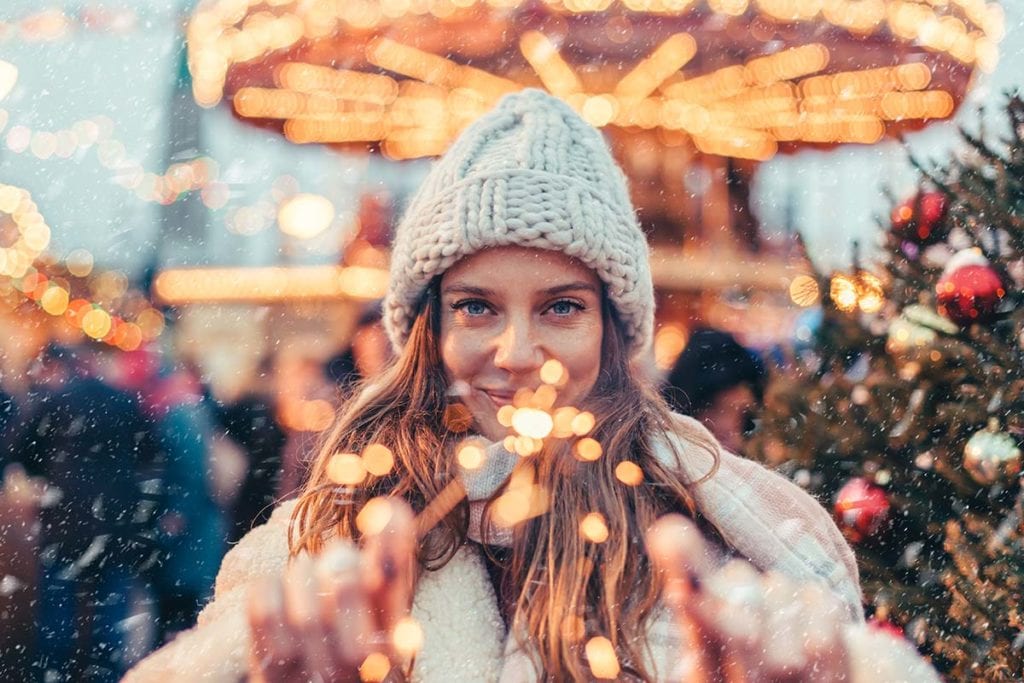 A woman stands in front of a merry go round and enjoys the benefits of sober holidays