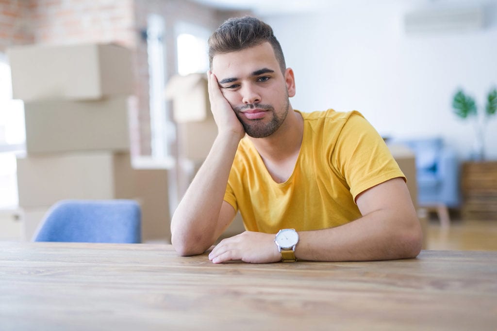 man at table thinking dejectedly about common relapse triggers