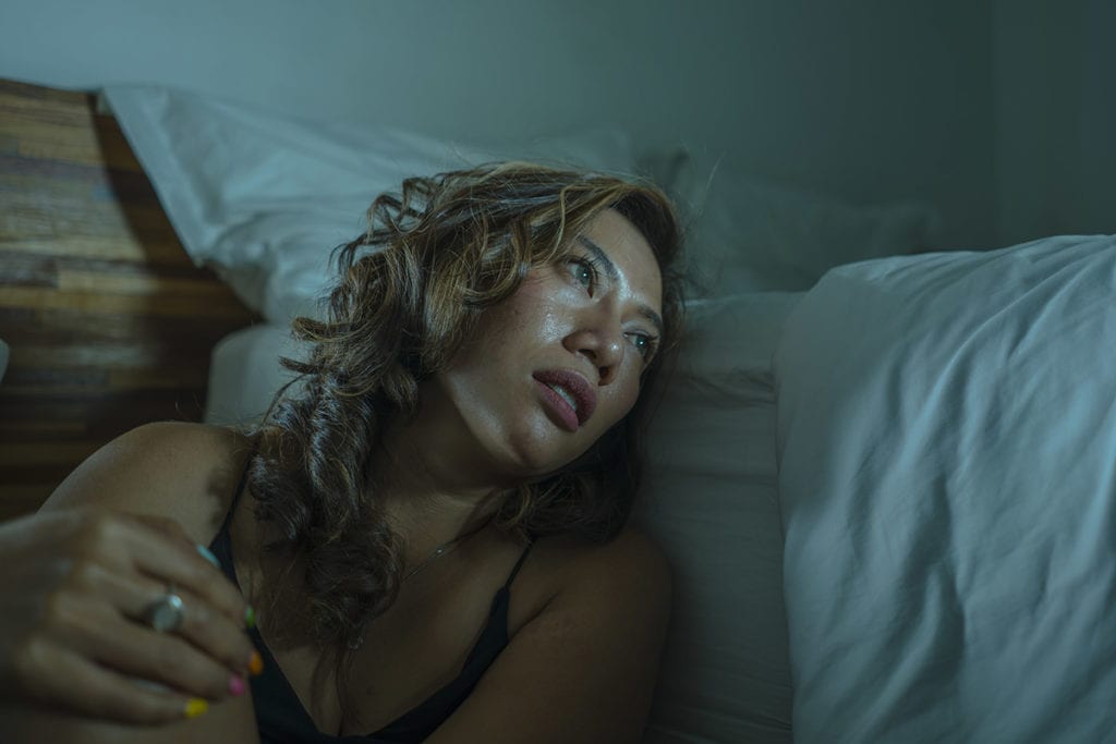 woman slumped on the floor leaning against bed wondering about signs of codependency