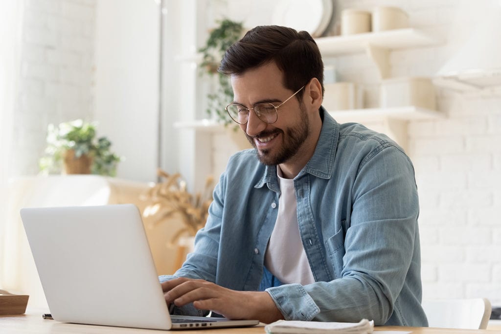 man smiling using laptop coping with isolation during coronavirus