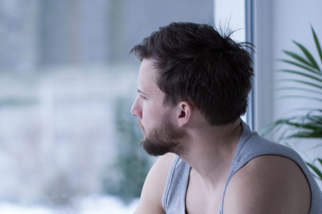 man staring out window showing signs of depression
