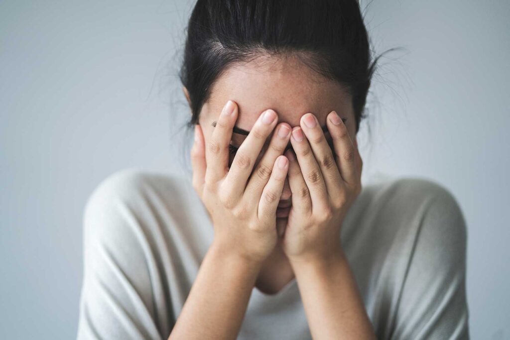 Person with hands on their face as they're being confronted with their defects of character