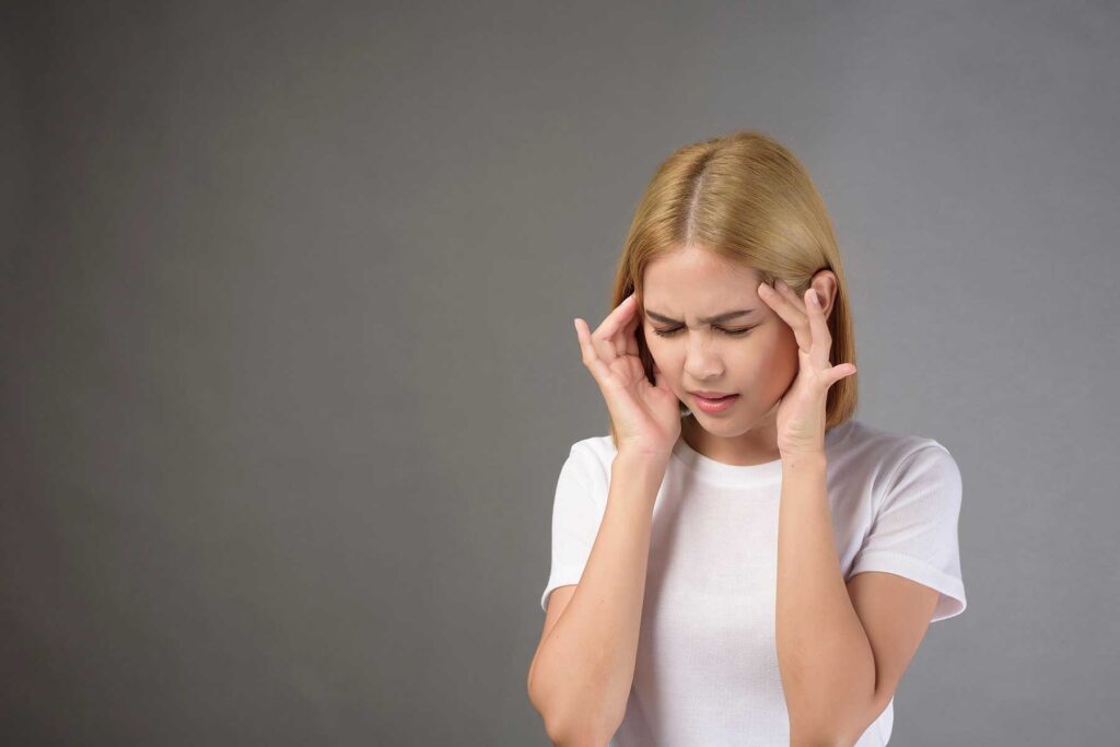 Person with hands to forehead, thinking about the signs of kratom addiction they're displaying