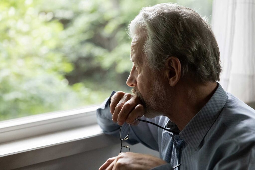 Person looking out window and thinking about depression symptoms in men