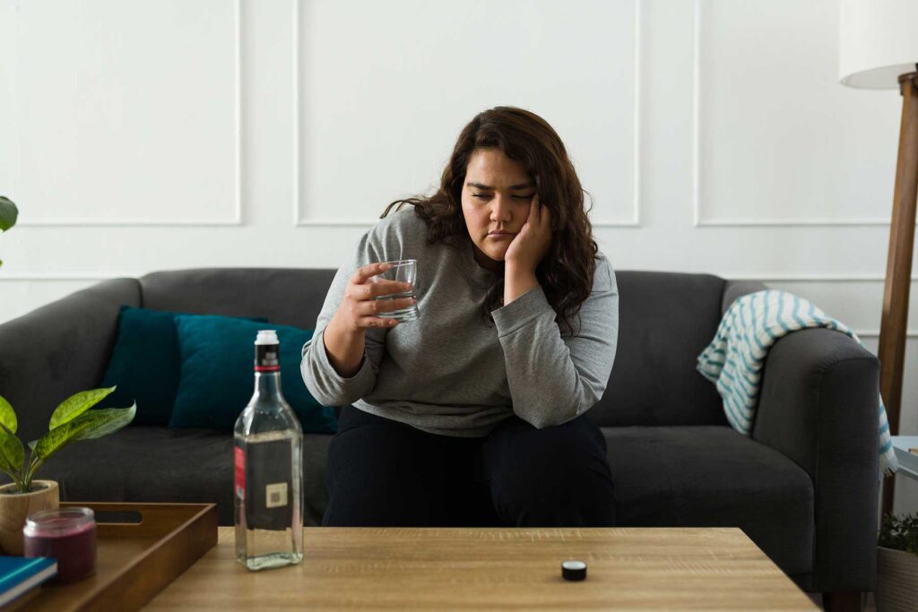 Person sitting on couch and thinking about the connection between anxiety and addiction