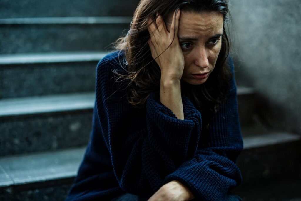 Person sitting on steps and wondering what the difference is between alcoholic and drunk